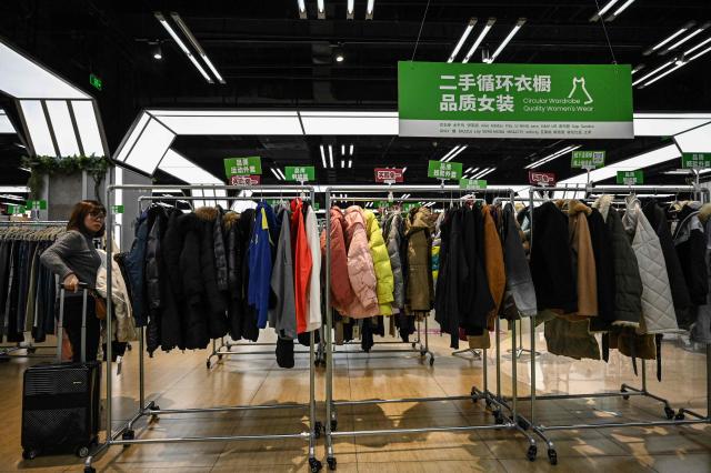 The photo taken on February 10, 2026 shows a woman browsing through the clothes section at a second-hand store in Shanghai. Boosting domestic consumption will be among key goals set forth by China's leaders at the annual Two Sessions political conclave this week, but they face an uphill battle. (Photo by Jade GAO / AFP) / To go with AFP story:  China-economy-politics-consumer-travel-retail, FOCUS by Jing Xuan TENG and Peter CATTERALL