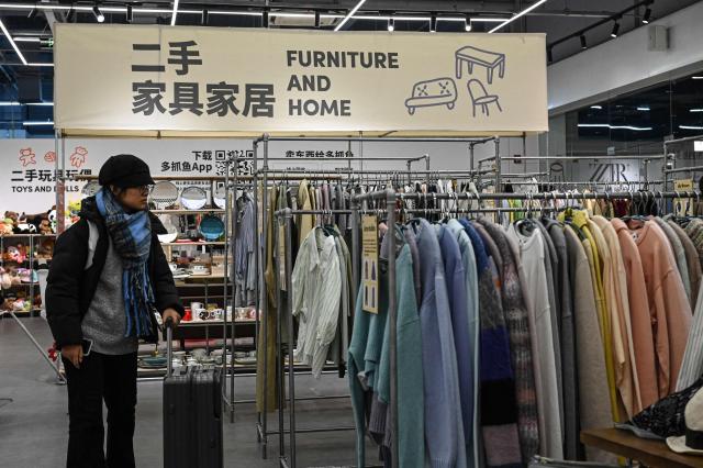 The photo taken on February 10, 2026 shows a woman browsing through the clothes section at a second-hand store in Shanghai. Boosting domestic consumption will be among key goals set forth by China's leaders at the annual Two Sessions political conclave this week, but they face an uphill battle. (Photo by Jade GAO / AFP) / To go with AFP story:  China-economy-politics-consumer-travel-retail, FOCUS by Jing Xuan TENG and Peter CATTERALL