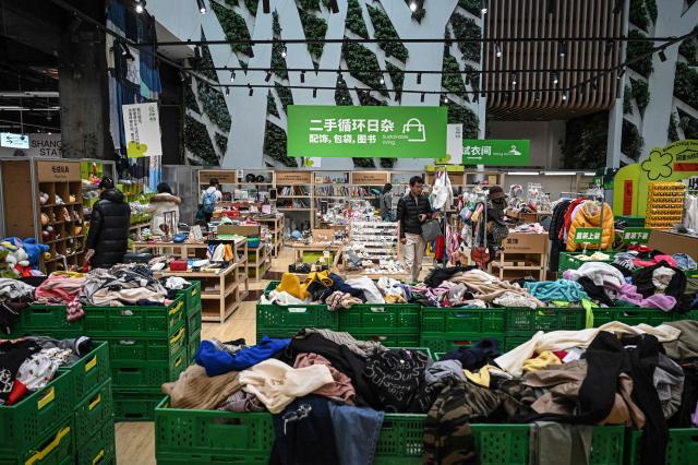 The photo taken on February 10, 2026 shows people browsing through products at a second-hand store in Shanghai. Boosting domestic consumption will be among key goals set forth by China's leaders at the annual Two Sessions political conclave this week, but they face an uphill battle. (Photo by Jade GAO / AFP) / To go with AFP story:  China-economy-politics-consumer-travel-retail, FOCUS by Jing Xuan TENG and Peter CATTERALL