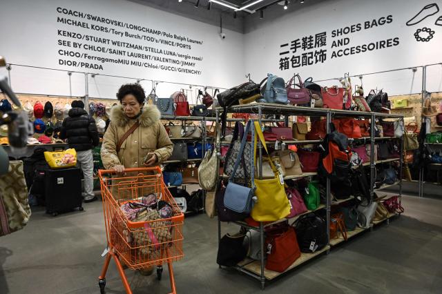 The photo taken on February 10, 2026 shows people browsing through luxury bags at a second-hand store in Shanghai. Boosting domestic consumption will be among key goals set forth by China's leaders at the annual Two Sessions political conclave this week, but they face an uphill battle. (Photo by Jade GAO / AFP) / To go with AFP story:  China-economy-politics-consumer-travel-retail, FOCUS by Jing Xuan TENG and Peter CATTERALL