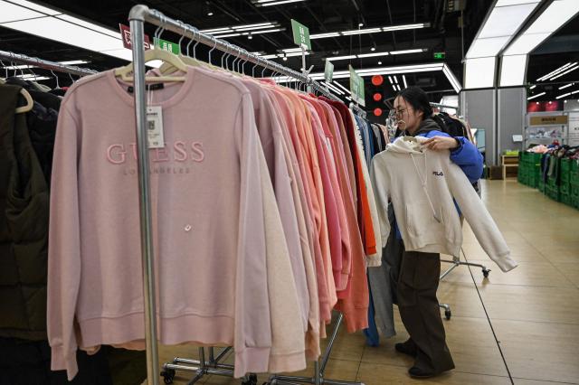 The photo taken on February 10, 2026 shows an employee sorting clothes at a second-hand store in Shanghai. Boosting domestic consumption will be among key goals set forth by China's leaders at the annual Two Sessions political conclave this week, but they face an uphill battle. (Photo by Jade GAO / AFP) / To go with AFP story:  China-economy-politics-consumer-travel-retail, FOCUS by Jing Xuan TENG and Peter CATTERALL
