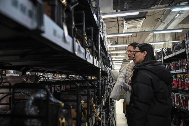 The photo taken on February 10, 2026 shows people browsing through luxury bags at a second-hand store in Shanghai. Boosting domestic consumption will be among key goals set forth by China's leaders at the annual Two Sessions political conclave this week, but they face an uphill battle. (Photo by Jade GAO / AFP) / To go with AFP story:  China-economy-politics-consumer-travel-retail, FOCUS by Jing Xuan TENG and Peter CATTERALL