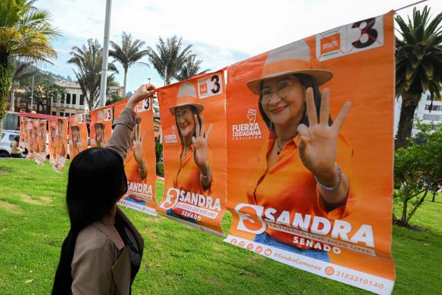 A supporter of Sandra Ramirez, candidate for the Senate of Colombia for the Fuerza Ciudadana party, and widow of Revolutionary Armed Forces of Colombia (FARC) top commander Manuel Marulanda, aka Tiro Fijo, hangs a poster during her campaigns closing event in Bogota on March 1, 2026. Sandra Ramirez dances, waves flags and gives speeches in squares. For the first time, the senator and former guerrilla fighter must win votes for Colombia's legislative elections, the FARC party's last political card to avoid disappearing. (Photo by Luis ACOSTA / AFP)
