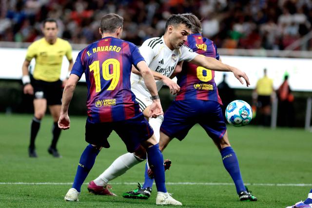 Real Madrid's Spanish forward David Barral (C) runs with the ball past Barcelona's Spanish defender Fernando Navarro (L) and Dutch midfielder Phillip Cocu (R) during the exhibition friendly football match between Spain's Real Madrid Legends and Barcelona Legends at the Akron Stadium in Guadalajara, Mexico, on March 3, 2026. (Photo by Ulises Ruiz / AFP)