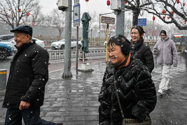 People walk outside the Forbidden city as it snows in Beijing on March 4, 2026. (Photo by Adek BERRY / AFP)