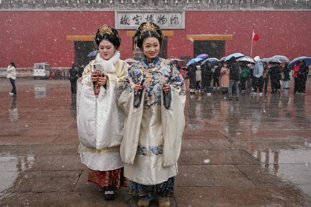 Women dressed in traditional costumes visit the Forbidden city as it snows in Beijing on March 4, 2026. (Photo by Adek BERRY / AFP)
