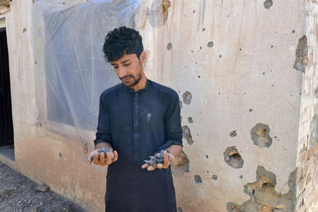 This picture taken on March 3, 2026 shows a resident displaying pieces of a mortar shell outside his damaged home in Landi Kotal near the Torkham border between Afghanistan and Pakistan, amid the ongoing clashes between the two countries. (Photo by Basit SHAH / AFP)