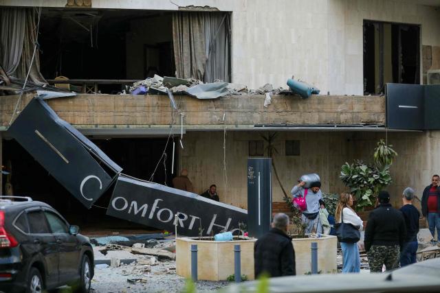 People leave a hotel after it was hit by an Israeli airstrike in Hazmieh, east of Beirut, on March 4, 2026. Israel launched fresh strikes on Iran and Lebanon, where state media reported a residential building was hit on March 4, as Iran's Guards said they had sealed off one of the world's most vital shipping routes for energy. (Photo by Ibrahim AMRO / AFP)