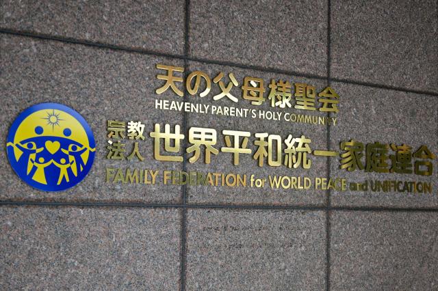(FILES) This file photo taken on September 22, 2022 shows the logo of the Family Federation for World Peace and Unification (FFWPU), widely known as the Unification Church, at the entrance of its Japan branch headquarters in Tokyo. The Unification Church lost an appeal on March 4, 2026, against a Japanese court's decision to strip the sect of official recognition, in the wake of the assassination of ex-premier Shinzo Abe. (Photo by Kazuhiro NOGI / AFP)