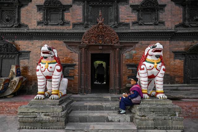 A woman looks on next to statues at Durbar Square in Kathmandu on March 4, 2026, a day before Nepal's general election. Nepal set up polling centres on March 4 for one of its most hotly contested elections since the end of civil war in 2006, six months after deadly anti-corruption protests toppled the government. (Photo by TAUSEEF MUSTAFA / AFP)