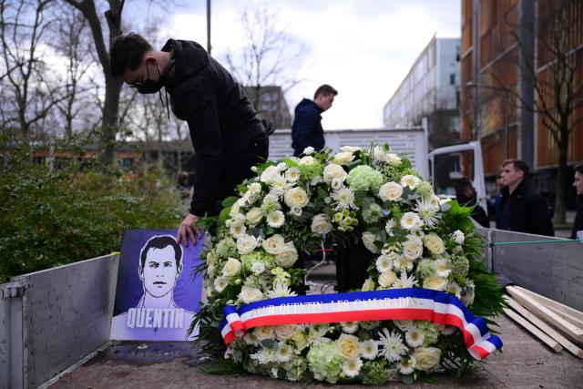 (FILES) A man stands next to a wreath of flowers ahead of a march in tribute to far-right activist Quentin Deranque, who died after being attacked on the sidelines of a far-right protest against a La France Insoumise (LFI) event at Sciences Po Lyon, in Lyon on February 21, 2026. Two men suspected of having taken part in the violence against radical far-right activist Quentin Deranque in Lyon were arrested on March 4, 2026, two weeks after a first wave of arrests, police sources told AFP. (Photo by OLIVIER CHASSIGNOLE / AFP)