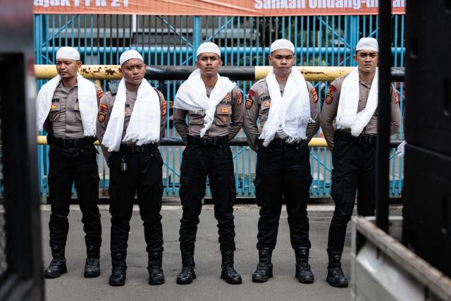 Police officers wearing white religious attire during the Muslim holy month of Ramadan stand guard during a labour union protest in Jakarta on March 4, 2026. (Photo by YASUYOSHI CHIBA / AFP)