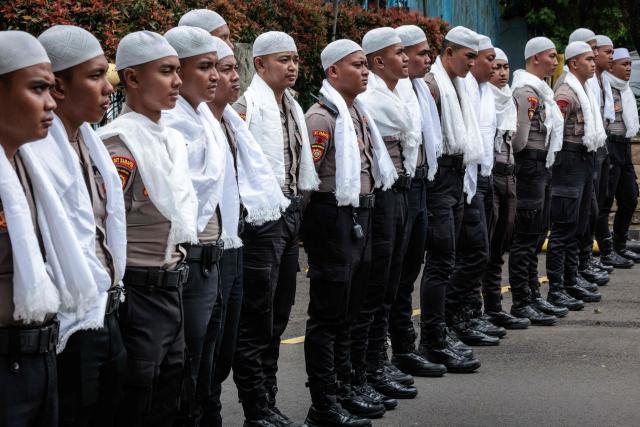 Police officers wearing white religious attire during the Muslim holy month of Ramadan stand guard during a labour union protest in Jakarta on March 4, 2026. (Photo by YASUYOSHI CHIBA / AFP)