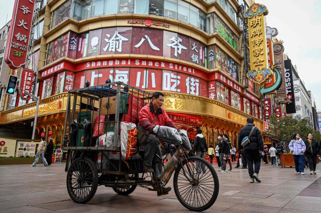 A man rides a tricycle on the Nanjing Road Pedestrian Street in Shanghai on March 4, 2026. (Photo by Jade GAO / AFP)
