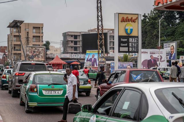 People walk past an electoral posters in Brazzaville on March 3, 2026, ahead of the country's March 15 presidential election. Congo-Brazzaville, a former French colony which gained independence in 1960, is rich in oil but nearly half of its six million people live below the poverty line. (Photo by Glody MURHABAZI / AFP)