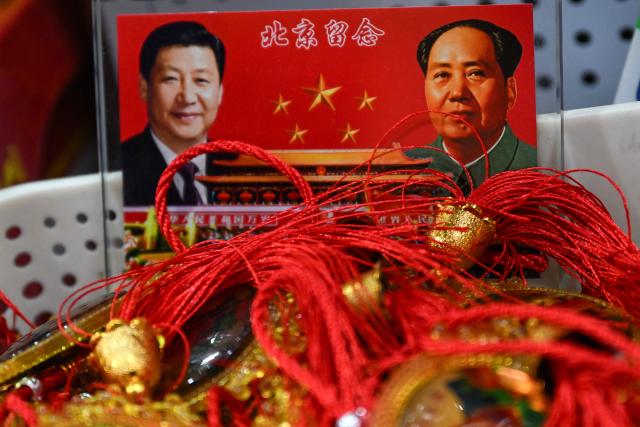 Portraits of China's President Xi Jinping (L) and late communist leader Mao Zedong are seen at a souvenir shop in a tourist area of Beijing on March 4, 2026. (Photo by Pedro PARDO / AFP)