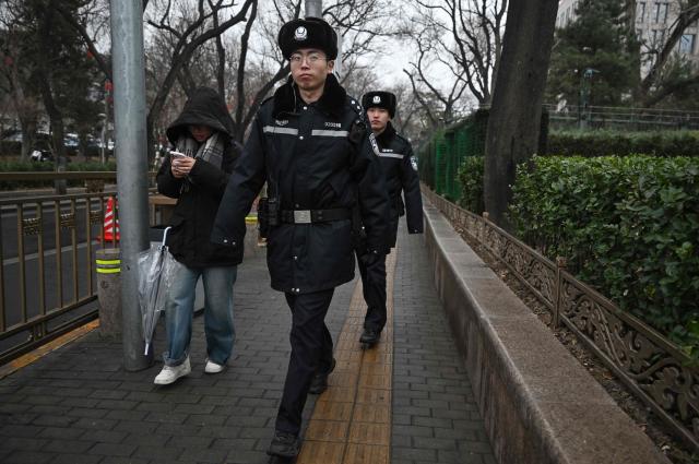 Policemen patrol in a street surrounding the Great Hall of the People where the opening of the Chinese People's Political Consultative Conference (CPPCC) takes place, in Beijing on March 4, 2026. (Photo by Pedro PARDO / AFP)