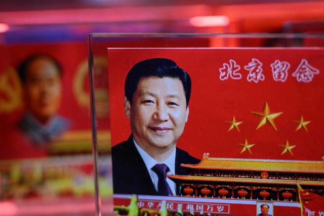 Portraits of China's President Xi Jinping (R) and late communist leader Mao Zedong are seen at a souvenir shop in a tourist area of Beijing on March 4, 2026. (Photo by Pedro PARDO / AFP)