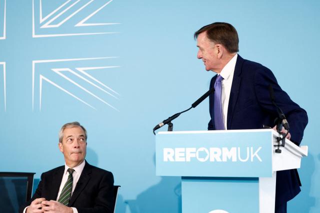Reform UK's leader Nigel Farage listens as former Labour local authority Mayor for Newham, Robin Wales, speaks at party press conference in central London on March 4, 2026, where he announced his defection to Reform. (Photo by Brook Mitchell / AFP)