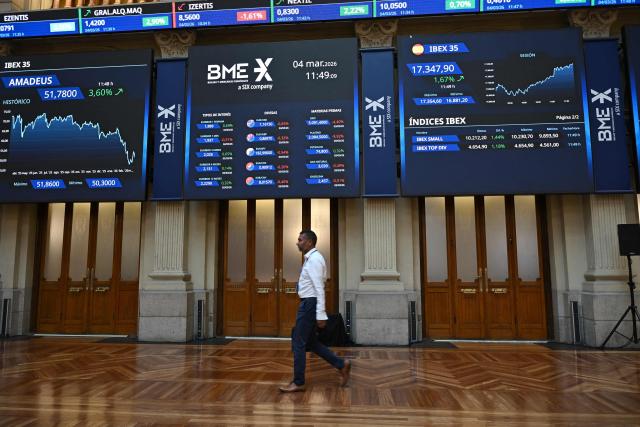 A person walks past at the Madrid Stock Exchange in Madrid on March 4, 2026. Markets were down sharply across the world following the weekend U.S. and Israeli attacks on Iran, with oil prices rising. (Photo by JAVIER SORIANO / AFP)
