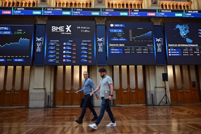 People walk past at the Madrid Stock Exchange in Madrid on March 4, 2026. Markets were down sharply across the world following the weekend U.S. and Israeli attacks on Iran, with oil prices rising. (Photo by JAVIER SORIANO / AFP)