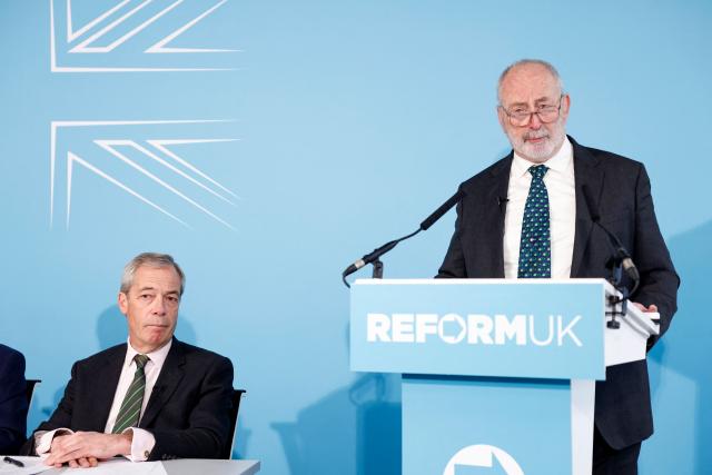 Reform UK's leader Nigel Farage listens as former Labour local councillor Clice Furness speaks at party press conference in central London on March 4, 2026, where he announced his defection to Reform. (Photo by Brook Mitchell / AFP)