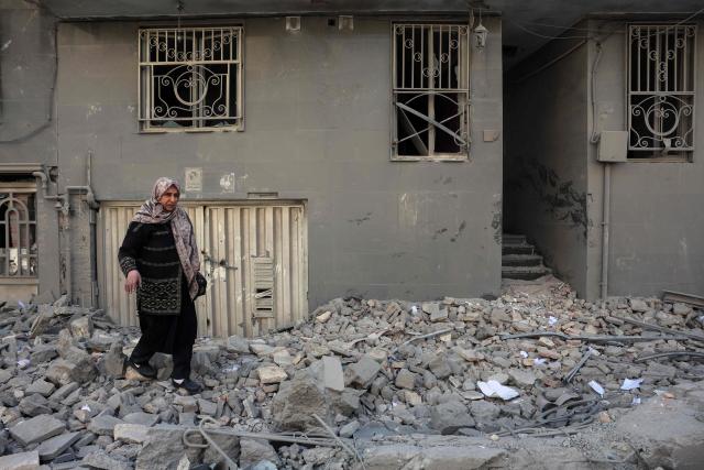 A woman makes her way through debris littering a street following airstrikes in central Tehran, on March 4, 2026. Iran's Revolutionary Guards said on March 4, they had total control of the Strait of Hormuz, a key waterway for global energy transit, as Israel launched a new wave of strikes on the Iranian capital. (Photo by AFP)