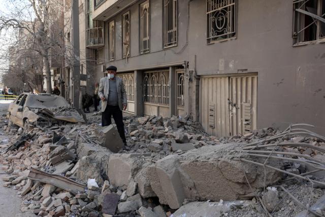 A man makes his way through debris littering a street following airstrikes in central Tehran, on March 4, 2026. Iran's Revolutionary Guards said on March 4, they had total control of the Strait of Hormuz, a key waterway for global energy transit, as Israel launched a new wave of strikes on the Iranian capital. (Photo by AFP)