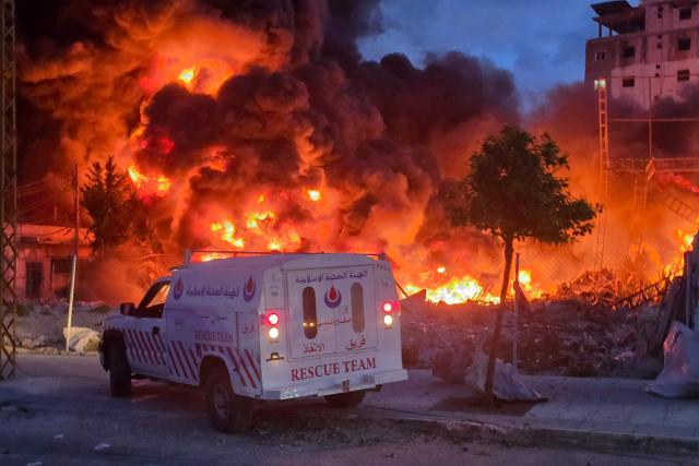 TOPSHOT - An ambulance is parked near a sweeping blaze following Israeli bombardment on a solar farm and electricity generation facility in Lebanon's southern coastal city of Tyre on March 4, 2026. Israeli forces on March 4 advanced into a number of towns and villages in south Lebanon, a source from the UN peacekeeping force in the country, UNIFIL, told AFP. (Photo by Kawnat HAJU / AFP)