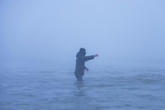 A smuggler waves to migrants after boarding a boat in an attempt to cross the English Channel off the beach of Gravelines, northern France, on March 4, 2026. (Photo by Sameer Al-DOUMY / AFP)