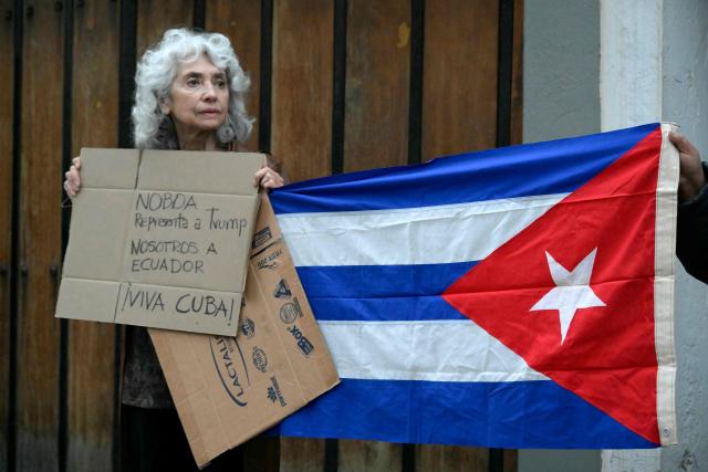 Former Ecuadorian ambassador to Cuba (2017-2019) Maria Augusta Calle protests alongside supporters of the Cuban government as they hold a Cuban flag outside the Cuban embassy in Quito on March 4, 2026. Ecuador ordered the expulsion of Cuba's ambassador to Quito, giving him and the rest of his embassy staff 48 hours to leave the country, the foreign ministry announced. (Photo by Rodrigo BUENDIA / AFP)