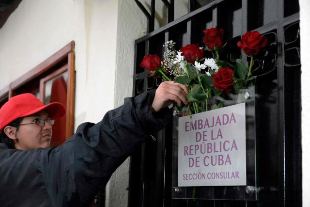 A supporter of the Cuban government places flowers at the door of the Cuban embassy in Quito on March 4, 2026. Ecuador ordered the expulsion of Cuba's ambassador to Quito, giving him and the rest of his embassy staff 48 hours to leave the country, the foreign ministry announced. (Photo by Rodrigo BUENDIA / AFP)