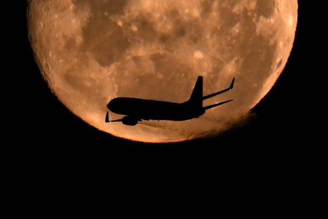 A Boeing 737 MAX 8 aircraft operated by Brazil’s airline GOL flies past the waning gibbous moon over Buenos Aires on March 4, 2026. (Photo by Luis ROBAYO / AFP)