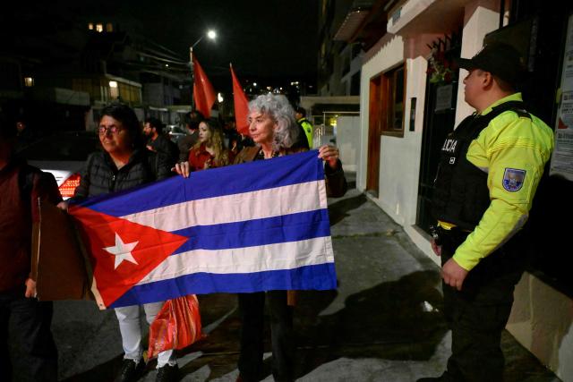 Former Ecuadorian ambassador to Cuba (2017-2019) Maria Augusta Calle (C) protests alongside supporters of the Cuban government as they hold a Cuban flag outside the Cuban embassy in Quito on March 4, 2026. Ecuador ordered the expulsion of Cuba's ambassador to Quito, giving him and the rest of his embassy staff 48 hours to leave the country, the foreign ministry announced. (Photo by Rodrigo BUENDIA / AFP)