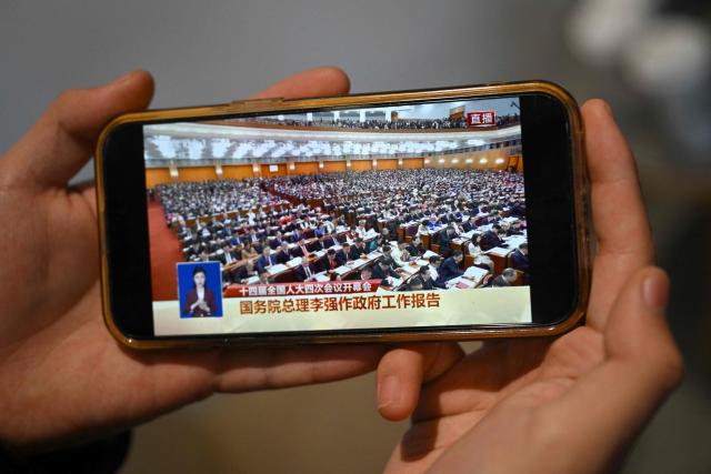 A man watches a live broadcast of the opening session of the National People's Congress (NPC), at a cafe in Beijing on March 5, 2026. (Photo by Pedro PARDO / AFP)