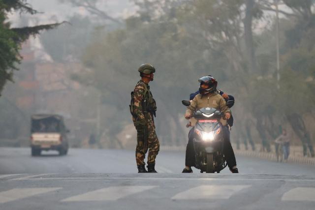 A member of security stops two men on a motorcycle on a road as polls open for Nepal's parliamentary election in Kathmandu on March 5, 2026. Nepal voted on March 5 for a new parliament, six months after deadly anti-corruption protests toppled the government -- a high-stakes showdown between an entrenched old guard and a powerful youth movement. (Photo by PRABIN RANABHAT / AFP)