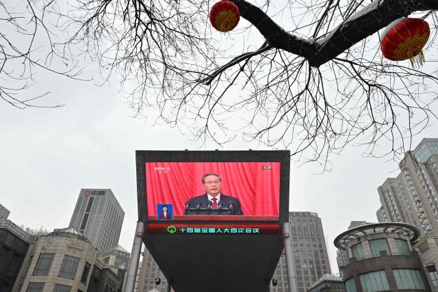 A screen shows Chinese Premier Li Qiang delivering a work report during the opening session of the National People’s Congress (NPC) at the Great Hall of the People, in Beijing on March 5, 2026. (Photo by ADEK BERRY / AFP)