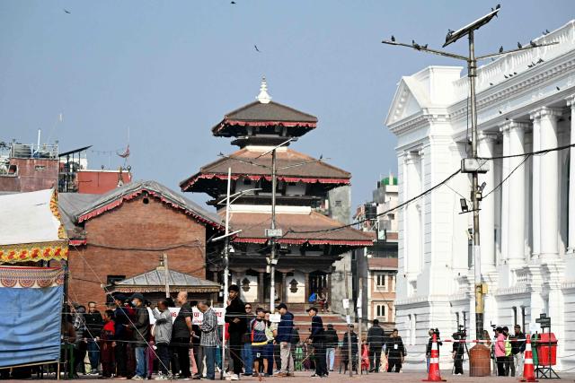 People stand in a queue as they wait to cast their ballot at a polling station during Nepal's parliamentary election in Kathmandu on March 5, 2026. Nepal voted on March 5 for a new parliament, six months after deadly anti-corruption protests toppled the government -- a high-stakes showdown between an entrenched old guard and a powerful youth movement. (Photo by TAUSEEF MUSTAFA / AFP)