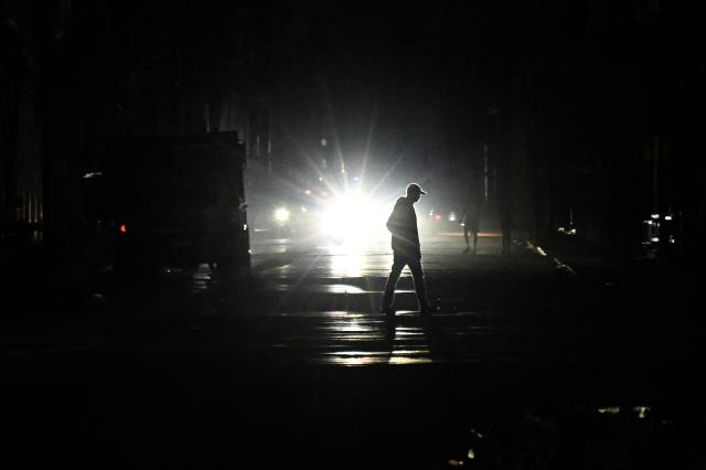 A man crosses a dark street during a blackout in Havana on March 4, 2026. (Photo by Yamil LAGE / AFP)
