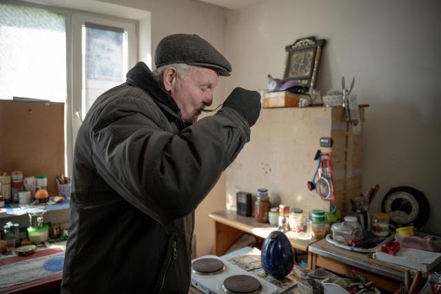 Grygory Gladysh, 79, the sole remaining resident of a heavily damaged 16-storey apartment building on the outskirts of Kharkiv, stands in the kitchen of his apartment where he has been living despite the lack of heating and water supply, on February 27, 2026, amid the Russian invasion of Ukraine. While millions of Ukrainians have been displaced internally or sought refuge abroad since the war began, many in dangerous areas are staying put, particularly elderly residents who lack the means or motivation to leave. (Photo by Ivan SAMOILOV / AFP)