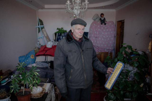 Grygory Gladysh, 79, the sole remaining resident of a heavily damaged 16-storey apartment building on the outskirts of Kharkiv, shows a thermometer indicating the temperature inside his apartment where he has been living despite the lack of heating and water supply, on February 27, 2026, amid the Russian invasion of Ukraine. While millions of Ukrainians have been displaced internally or sought refuge abroad since the war began, many in dangerous areas are staying put, particularly elderly residents who lack the means or motivation to leave. (Photo by Ivan SAMOILOV / AFP)