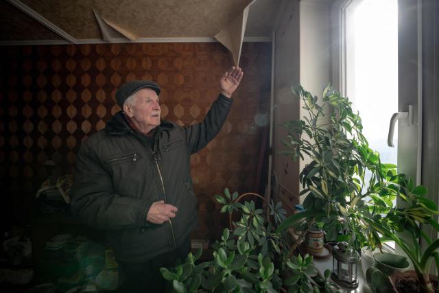 Grygory Gladysh, 79, the sole remaining resident of a heavily damaged 16-storey apartment building on the outskirts of Kharkiv, surveys a damage to his apartment where he has been living despite the lack of heating and water supply, on February 27, 2026, amid the Russian invasion of Ukraine. While millions of Ukrainians have been displaced internally or sought refuge abroad since the war began, many in dangerous areas are staying put, particularly elderly residents who lack the means or motivation to leave. (Photo by Ivan SAMOILOV / AFP)