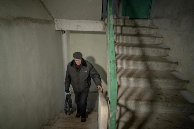 Grygory Gladysh, 79, the sole remaining resident of a heavily damaged 16-storey apartment building on the outskirts of Kharkiv, walks up a stairway to his apartment where he has been living despite the lack of heating and water supply, on February 27, 2026, amid the Russian invasion of Ukraine. While millions of Ukrainians have been displaced internally or sought refuge abroad since the war began, many in dangerous areas are staying put, particularly elderly residents who lack the means or motivation to leave. (Photo by Ivan SAMOILOV / AFP)