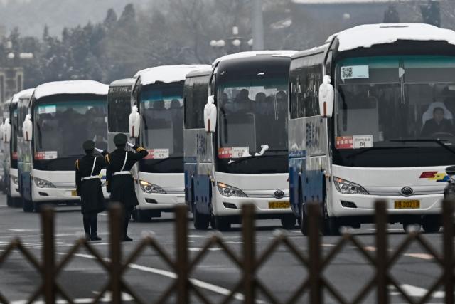 Delegates aboard buses leave the Great Hall of the People after the opening session of the National People's Congress (NPC) in Beijing on March 5, 2026. (Photo by Pedro PARDO / AFP)