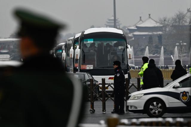 Delegates aboard buses leave the Great Hall of the People after the opening session of the National People's Congress (NPC) in Beijing on March 5, 2026. (Photo by Pedro PARDO / AFP)