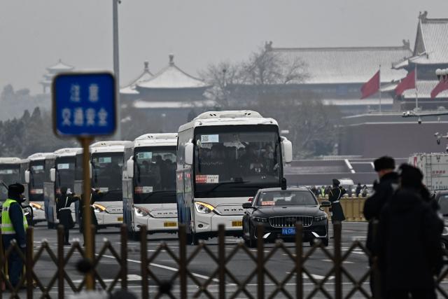 Delegates aboard buses leave the Great Hall of the People after the opening session of the National People's Congress (NPC) in Beijing on March 5, 2026. (Photo by Pedro PARDO / AFP)