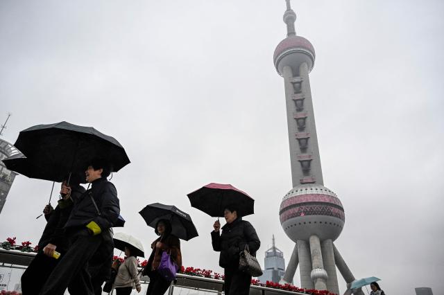 People walk past the Oriental Pearl Tower at the financial district of Lujiazui in Shanghai on March 5, 2026. (Photo by Jade GAO / AFP)
