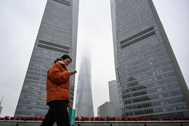A woman walks on an overpass at the financial district of Lujiazui in Shanghai on March 5, 2026. (Photo by Jade GAO / AFP)