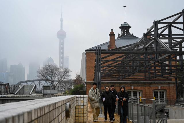 People walk along the Suzhou River as the Oriental Pearl Tower is seen behind in Shanghai on March 5, 2026. (Photo by Jade GAO / AFP)