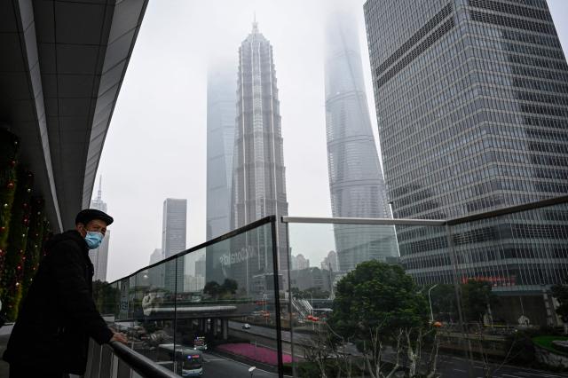 A man holds onto the railing on an overpass at the financial district of Lujiazui in Shanghai on March 5, 2026. (Photo by Jade GAO / AFP)
